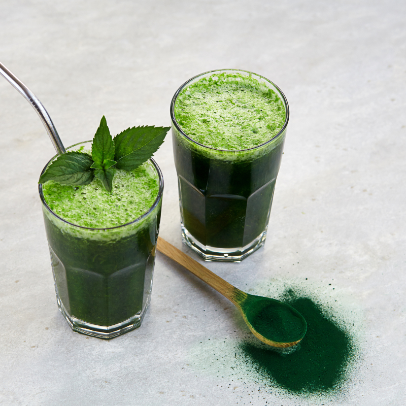 Zwei Trinkgläser gefüllt mit in Wasser aufgelöstem Chlorella-Pulver