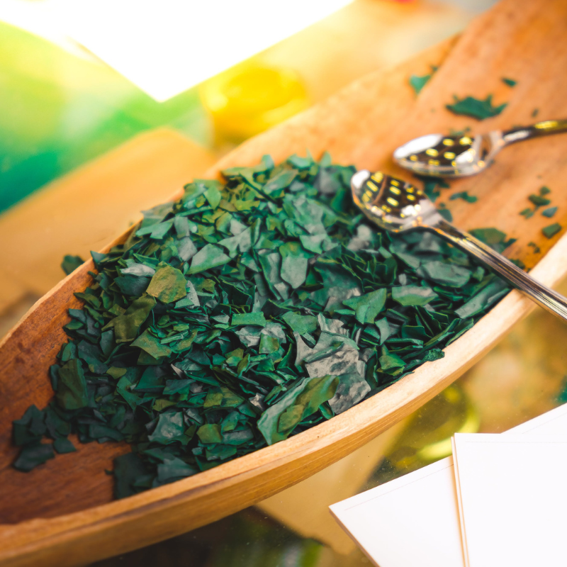 Getrocknete und geschrotete Chlorella-Algen in einer Holzschale