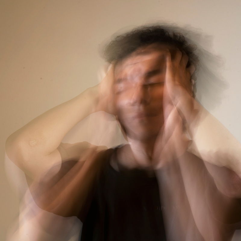 Mann hält sich vor Stress den Kopf, alles um ihn herum verschwimmt